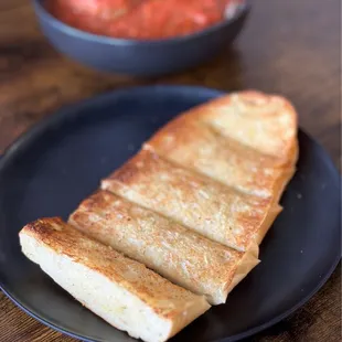 a piece of bread and a bowl of tomato sauce