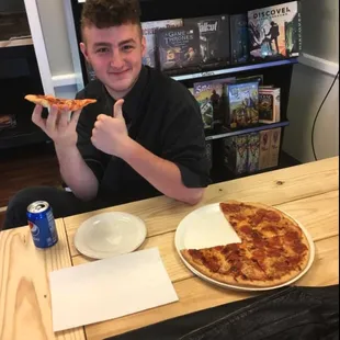a man sitting at a table with a slice of pizza