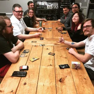 a group of people sitting around a wooden table