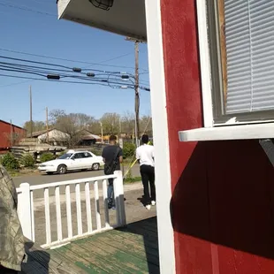 a man standing on a porch in front of a red house