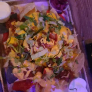 a plate of nachos with cheese, tomatoes, onions, and lettuce