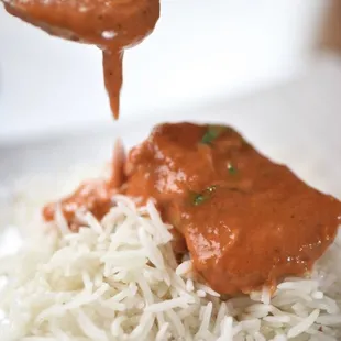 a spoon drizzling sauce over rice