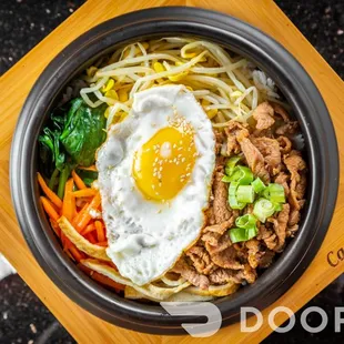 an overhead view of a bowl of noodles with a fried egg