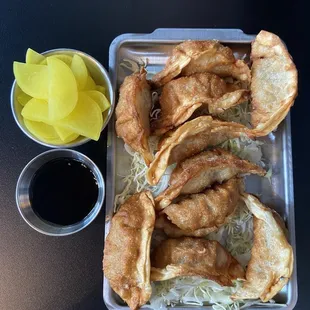Fried mandu with sauce and sliced pickled radishes.