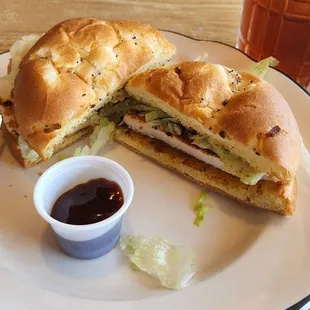 Cajun chicken sandwich with little cup of BBQ sauce to keep it company.