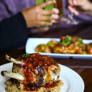 Pork Chop and Half Roasted Chicken with Guests Toasting in the background