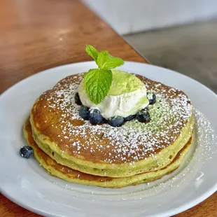 MATCHA PANCAKES with blueberries, whipped cream and powdered sugar.
