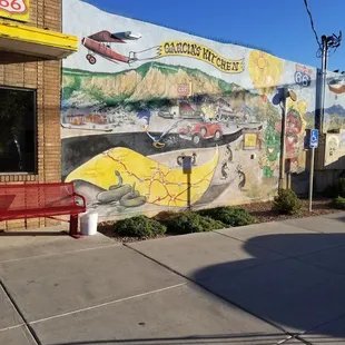a red bench in front of a mural