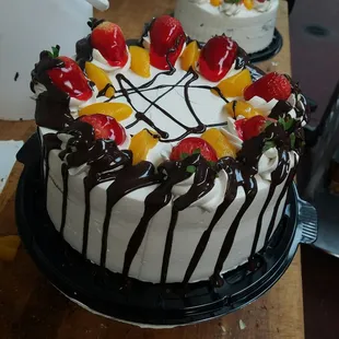 a cake decorated with strawberries, oranges, and chocolate