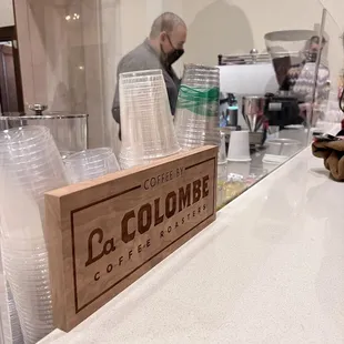 a man standing behind a counter with cups of coffee