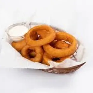a basket of onion rings with dip