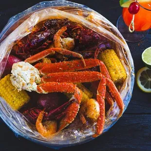 a bowl of crab legs, corn, and lemons