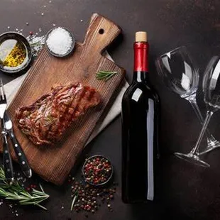 a steak on a cutting board with a bottle of wine
