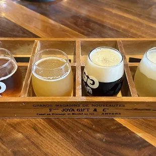 four glasses of beer in a wooden box