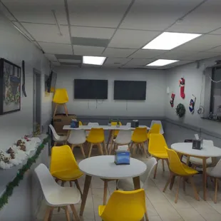a dining area with yellow chairs and white tables