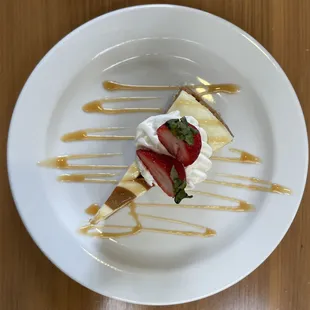 a slice of cheesecake with whipped cream and strawberries