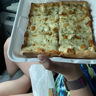a person holding a box of pizza