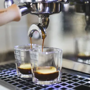 espressor pouring coffee into shot glasses