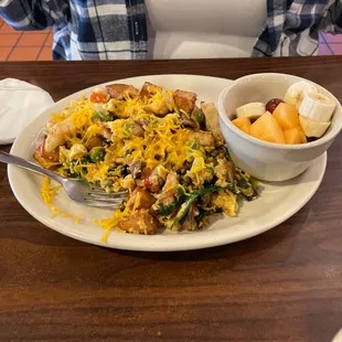 Chicken scramble. Has mushrooms, chicken, eggs, potatoes, spinach, bell peppers, onions, and cheese.  Fruit side.
