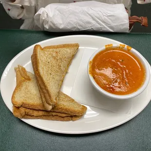 Homemade grilled cheese on white bread with homemade in the house from scratch tomato soup.