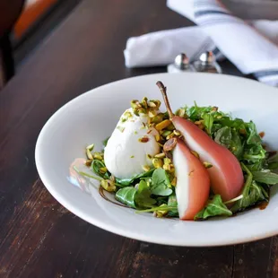 a plate of salad with pears and goat cheese