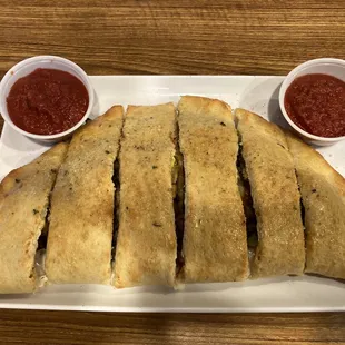 view of a supreme calzone, with double sides of surprisingly flavorless marinara sauce