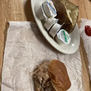 Sliced barbecue sandwich and huge baked potato