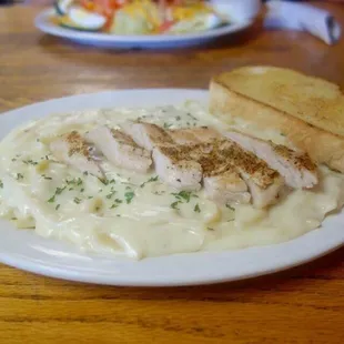 Chicken Alfredo with tender chicken and crispy garlic bread.