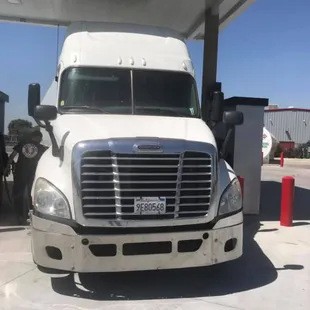 a white semi truck at a gas station