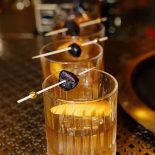 a glass of alcohol with a skewer