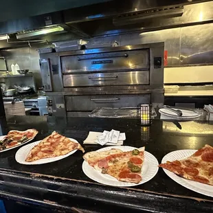 a row of plates of pizza on a counter