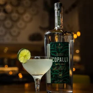 a cocktail in a glass with a lime garnish