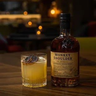 a glass of whiskey and a bottle of monkey shoulder