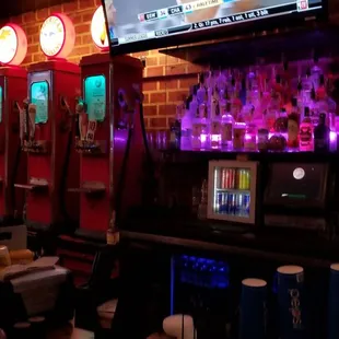 a bar with neon lights and televisions