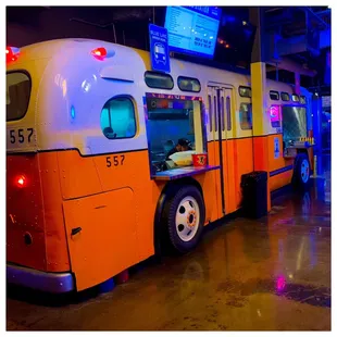 an orange and white bus in a museum