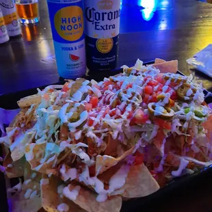 a plate of nachos and a can of corona beer