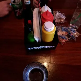 a person sitting at a table with drinks and condiments