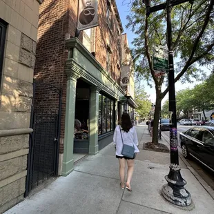 a woman walking down a sidewalk in front of a building