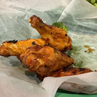 a basket of chicken wings and broccoli