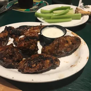 a plate of chicken wings, celery, and dip