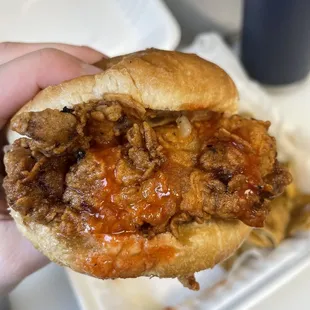 a hand holding a pulled pork sandwich