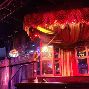 a stage with red drapes and a chandelier