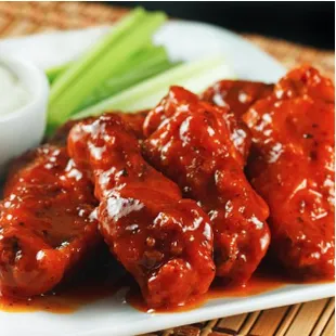 a plate of chicken wings with sauce and celery