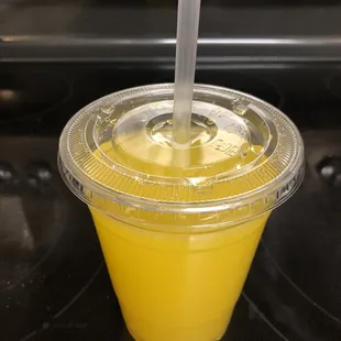 a yellow drink in a plastic cup