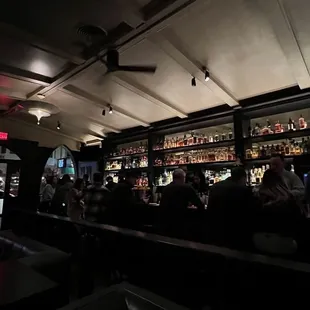 a dimly lit bar with people sitting at the bar