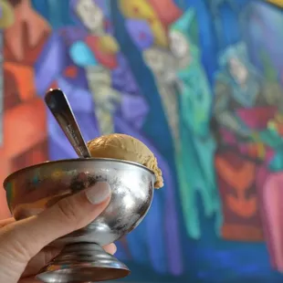 a hand holding a bowl of ice cream