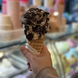 Single scoop marshmallow gelato with Oreo crumble in a waffle cone