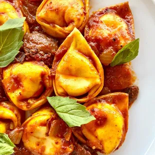 a plate of tortelli with basil leaves