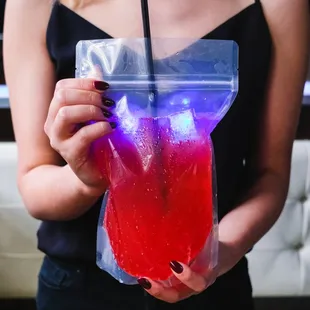 a woman holding a drink in a plastic bag