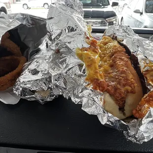 Onion rings and hot dog with Spanish sauce, onions, and cheese